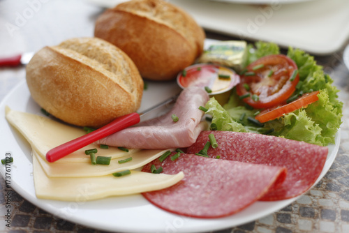 Delicious breakfast plate with bread rolls, cheese, and cold cuts
