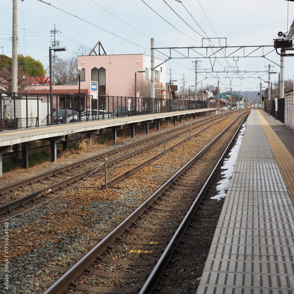 Fototapeta premium Local train station platform with railway tracks and remaining snow ローカル線 駅ホーム 線路と残雪