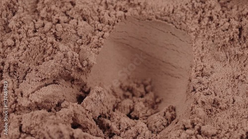 Take out a measuring spoon filled with chocolate protein powder. Macro close-up of sports nutrition supplement for fitness, healthy diet, muscle gain, workout recovery concept. Whey lean protein