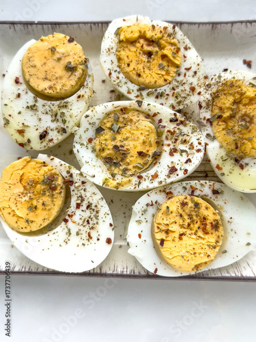 Halved Hard boiled eggs with spices and herbs on plate with copy space