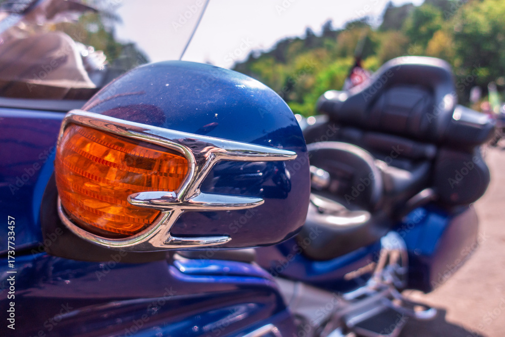 Fototapeta premium Close-up of a vibrant blue motorcycle's front fairing with a gleaming orange turn signal and chrome details, suggesting a classic or touring bike.