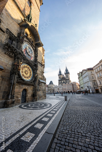 Stunning sunrise over Prague with warm golden light illuminating historic architecture, cobblestone streets, and iconic city landmarks in high-quality detail.