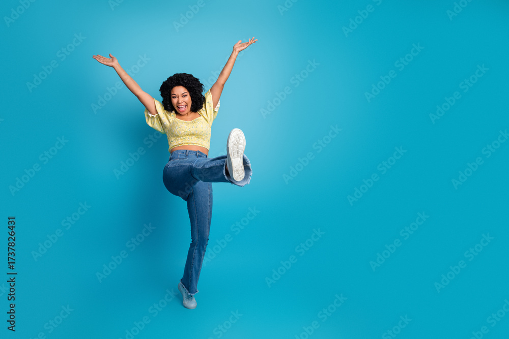 Obraz premium Excited young multiethnic woman posing playfully against a blue background showing a gesture of happiness and joy