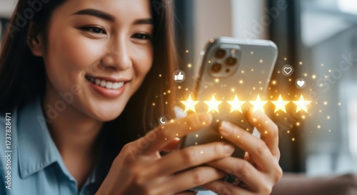 Smiling asian woman using smartphone showing five star rating experience online