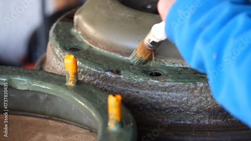 Person is painting a wheel with a brush. The wheel is green