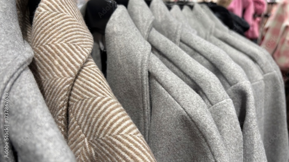 Obraz premium Warm autumn and winter coats on hangers in clothing store. Seasonal outerwear, fashion wardrobe update, preparation for cold weather, modern stylish coats