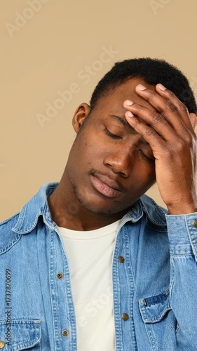 Unhappy adult man shaking his head over beige backdrop.