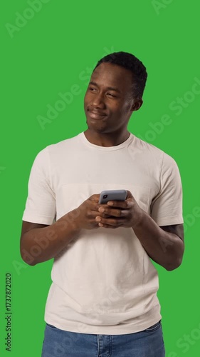 Adult man text messaging using his mobile his phone over green backdrop.