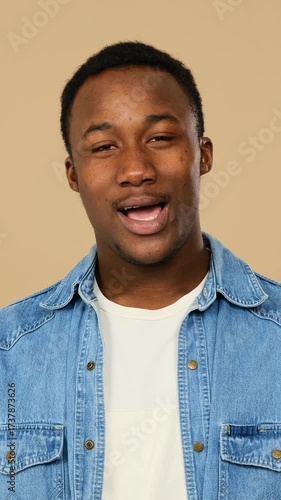 Adult man greeting and explaining over beige backdrop.