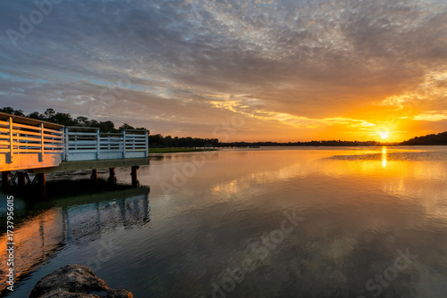 Wallpaper Mural Sunset view over calm water with dock and colorful sky near a peaceful shore in the evening Torontodigital.ca