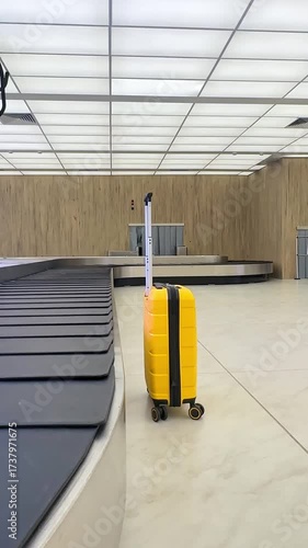 Yellow luggage near baggage carousel in airport arrived hall for baggage claim and traveling insurance business concept. Empty conveyor belt. Checked baggage, travel by aircraft. Vertical footage