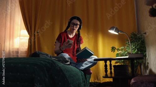 Young Caucasian student woman sits at desk at home in evening room with warm light concentrating on homework. Concept of home education, preparation for exams and university studies. Wide shot