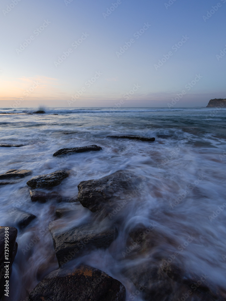 Obraz premium Wave coming through rocky beach shore.