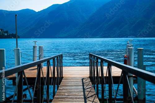 Boat pier on the Lake Lugano, Switzerland. Copy Space image. European vacation, travel and nautical concept. Alps mountains in the background. Clear view of the lake.