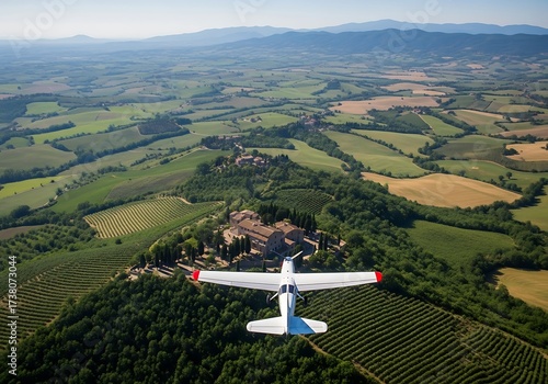 A small plane soars above rolling hills and vineyards, showcasing a picturesque Tuscan landscape.