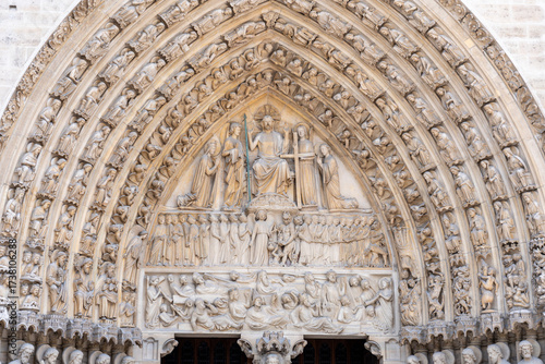 Decorative marble statues of saints, angels and demons carved around the entrance door of Notre Dame Cathedral in Paris