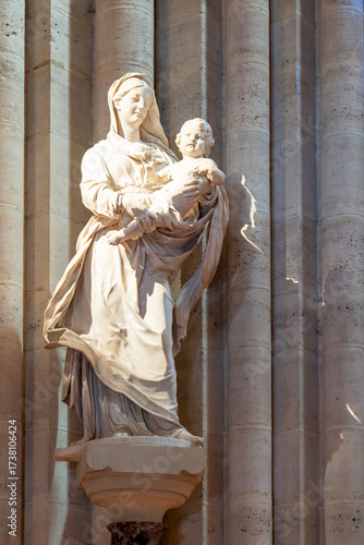 Marble statue of young Virgin Mary smiling while holding Jesus as a boy