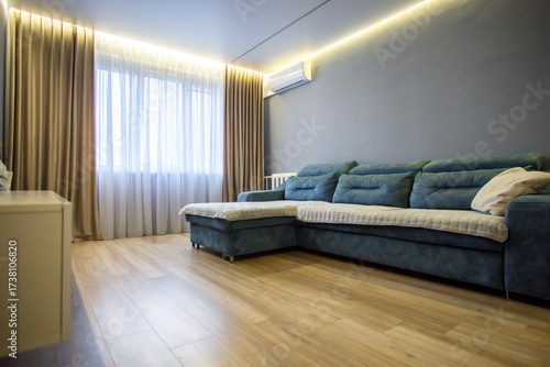 Stylish modern renovation in a living room against the background of a window with brown curtains and LED lighting on the ceiling. Copy space for text
