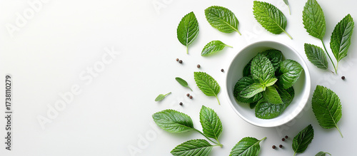 Fresh mint leaves in bowl, peppercorns, white background, healthy ingredient
