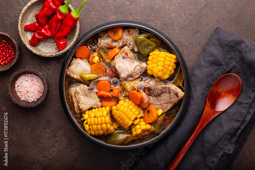 Chilean cuisine of Latin America. Traditional Chilean cazuela de cerdo. Pork soup with potatoes and corn, stew with corn, chili and carrots on dark background top view