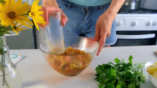 Woman pressing vegetables stew in bowl using glass cooking on kitchen. Culinary techniques, homemade preparing healthy meal cook food dish, cuisine, seasoning garlic parsley greenery.
