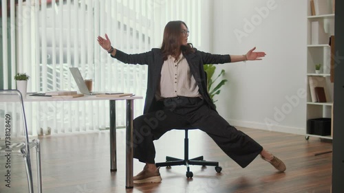 Office Ergonomics and Employee Wellness. Office Manager Performs Seated Side Leg and Lumbar Spine Stretch at Desk to Improve Flexibility, Support Posture, Reduce Discomfort and Promote a Balanced