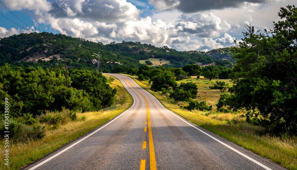 Fototapeta premium Winding road through countryside under a partly cloudy sky