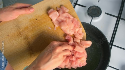Chef woman hands putting chicken breast pieces from cutting board into hot pan on kitchen. Culinary techniques, homemade preparing healthy meal cook meat food, organic cuisine from fresh ingredients.
