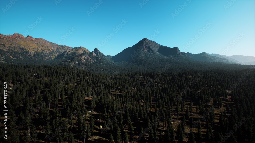 Fototapeta premium Majestic mountains rise over dense green forests, basking under a bright blue sky. Tranquility reigns as nature thrives, creating a perfect backdrop for outdoor adventures.