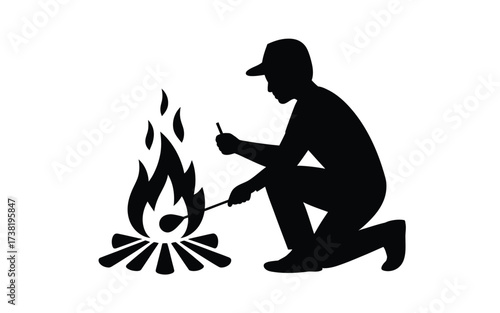 Silhouette of a person lighting a campfire outdoors in nature