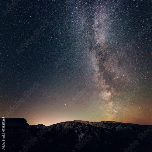 The vibrant Milky Way and a sky full of stars rise above a snowy mountain landscape at night.