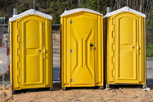 Three Yellow Portable Toilets on Construction Site