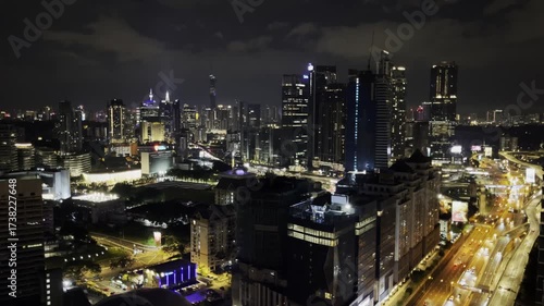 A nighttime view of Kuala Lumpur with illuminated skyscrapers, highways, and glowing city lights, showcasing the modern urban skyline of Malaysia