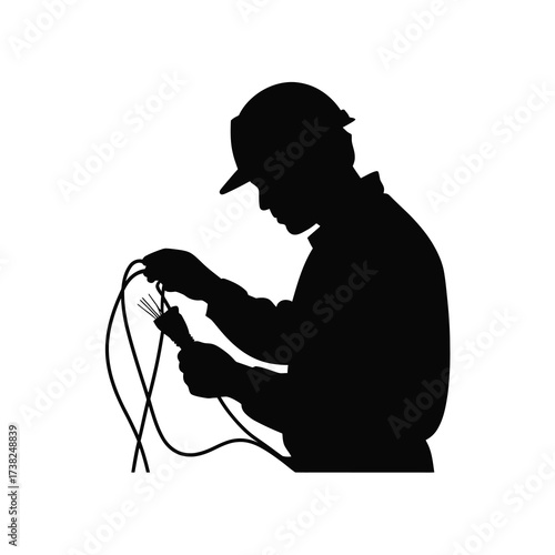 Silhouette of a skilled electrician working with wires wearing a hard hat