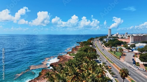 An aerial view of the beautiful coastal city of Santo Domingo, Dominican Republic. Drone view of modern city buildings and a road on the ocean coast. A picturesque seaside coastline with palm trees.