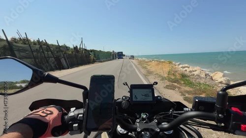 Motorcycle riding on an open countryside road under a bright summer sky.