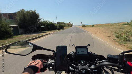 Motorcycle riding on an open countryside road under a bright summer sky.