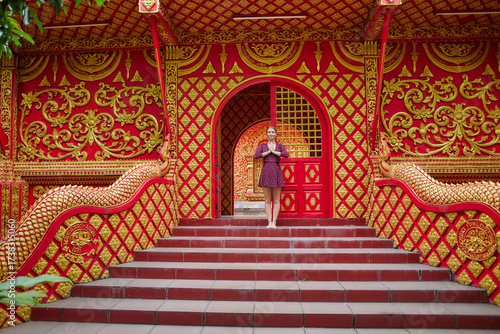A Woman Posing Gracefully at the Entrance of a Magnificent Red and Gold Architectural Structure Adorned with Intricate Patterns and Designs