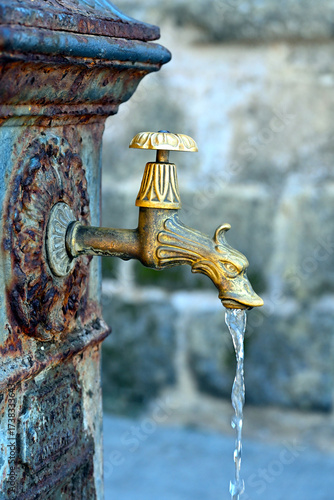 Drinking fountain on street of Alghero, Sardegna, Italy. Close-up of a decorative old faucet with flowing water