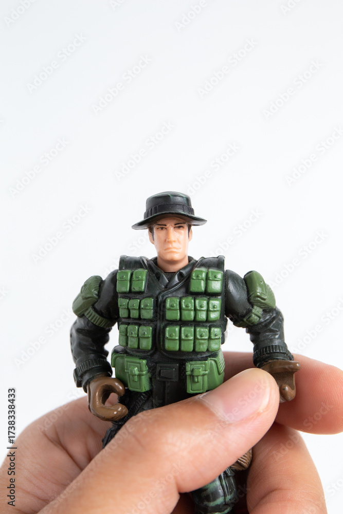 Fototapeta premium Boy hand holding mini toy soldiers on white background.