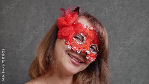 Beautiful woman 40-50 years old in red mask and black dress smiling and flirting