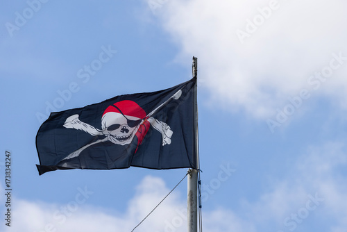 Black pirate flag waving against blue sky