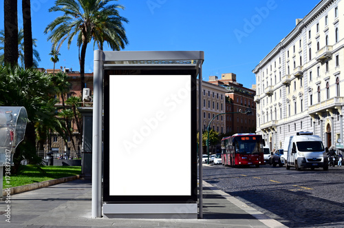 bus shelter with vertical blank ad panel. billboard display. empty white lightbox sign at bus stop. mockup base. city transit station. urban street. park setting with palm trees. outdoor advertising