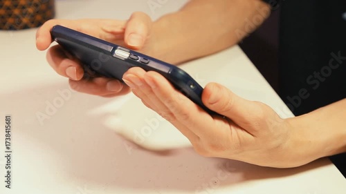 Closeup hands video of business woman holding in hands mobile phone in horizontal position and working, texting, chatting in office.  Businesswoman job concept