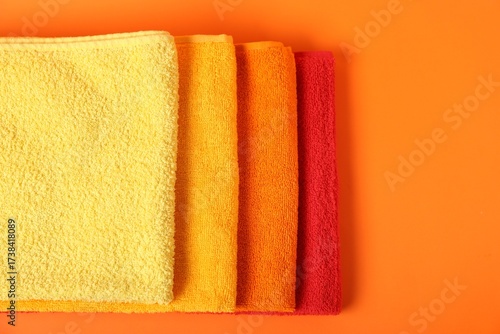 Photos Fresh terry towels on orange background, top view