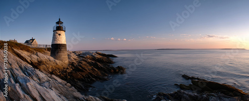 Scenic Coastal Lighthouse at Sunset with Rocky Cliffs and Calm Sea