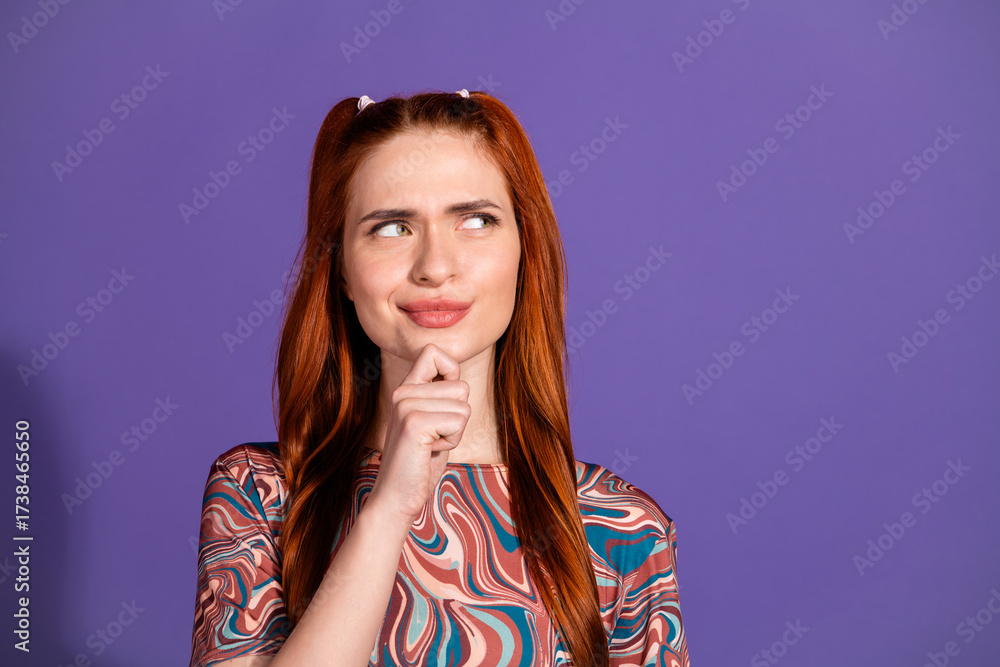 Fototapeta premium Young red-haired woman making a thoughtful gesture against a purple background, ideal for lifestyle or advertising themes
