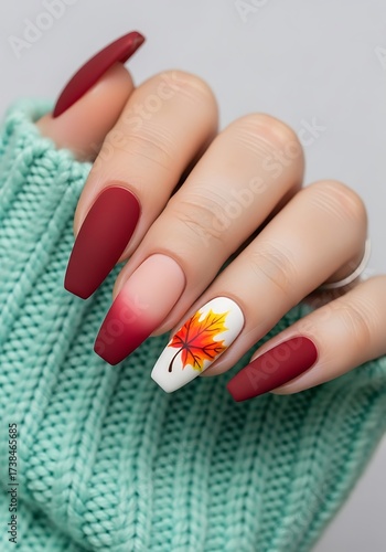 Elegant ombre red nails with autumn leaf art for a chic look