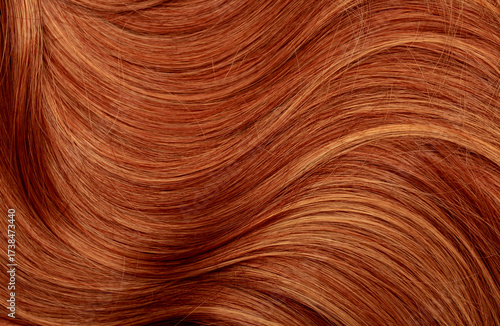 Red hair close-up as a background. Women's long orange hair. Beautifully styled wavy shiny curls. Hair coloring bright shades. Hairdressing procedures, extension.