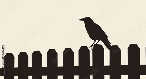 Silhouette of a crow perched on a wooden fence.